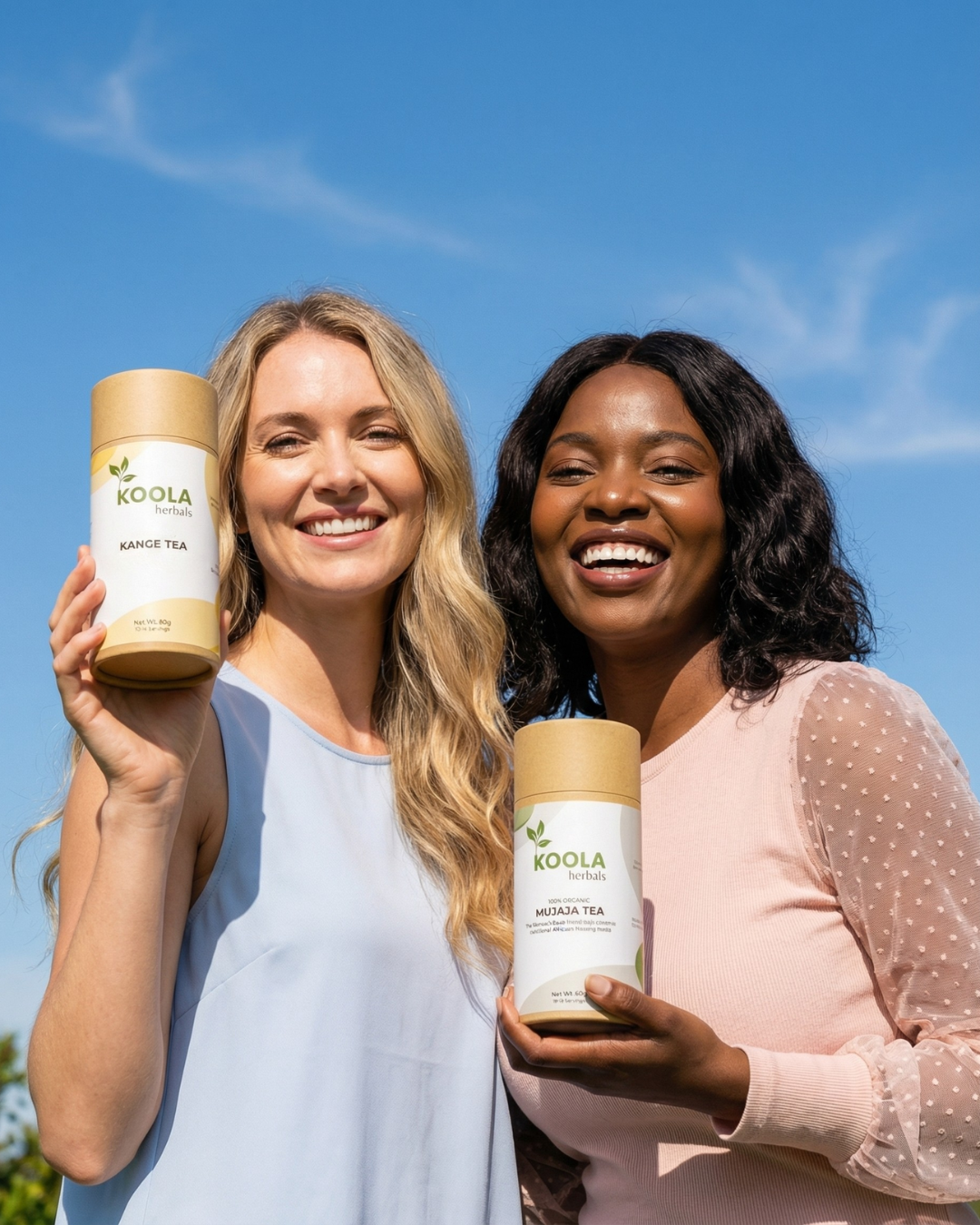 Two women holding Koola tea containers against a blue sky.